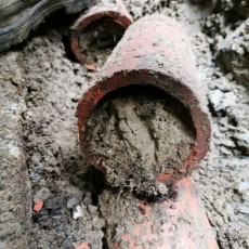 Drain-de-terre-cuite-bloqué-par-sable-et-racine-scaled